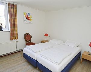 Helles Schlafzimmer im Ferienhaus De Oorsprong, Zuid-Eierland, Texel mit zwei Einzelbetten und dekorativen Elementen.