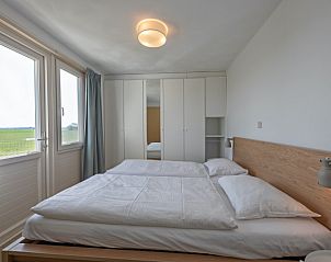 Slaapkamer met tweepersoonsbed in Huisje 7 in De Dennen, Texel biedt comfort en een prachtig uitzicht op de Waddeneilanden.