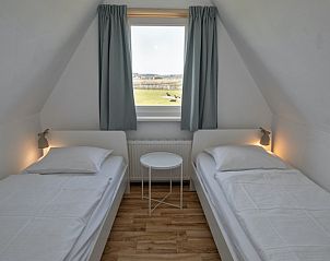 Slaapkamer met twee eenpersoonsbedden in Huisje 7 in De Dennen, Texel met uitzicht op de groene omgeving van de Waddeneilanden.