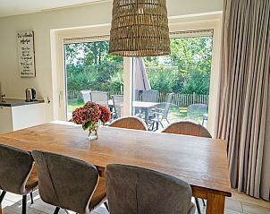 Eethoek in Vakantiehuis de Parel 150 in De Dennen, Texel met uitzicht op groene omgeving.