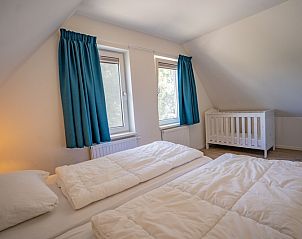 Ruime slaapkamer met babybedje in Vakantiehuis de Parel 150 in De Dennen, Texel.
