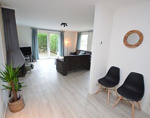 Gerumiges Wohnzimmer im Ferienhaus Bungalowpark Vredelust, De Dennen, Texel, mit bequemer Sitzgelegenheit und Gartenblick.