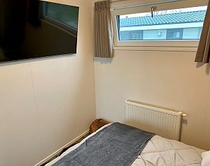 Slaapkamer met televisie in Vakantiepark de Bremakker - Bosveld 148, De Dennen, Texel voor ultiem comfort en ontspanning.