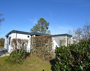 Vacation home de Parel 198 in De Dennen, Texel offers a serene outdoor view with green surroundings and blue sky.