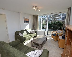 Cozy living room of Holiday home the Pearl 198 in De Dennen, Texel with comfortable green sofas and lots of natural light.