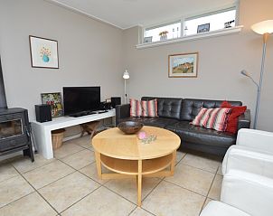 Cozy interior of Bungalow Uterste Coogh 78 in De Dennen, Texel, with a wood-burning stove and comfortable seating areas.