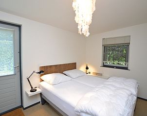 Comfortabele slaapkamer in Vakantiehuis 't Hoogelandt 202 - Aan Zee, Texel, met een tweepersoonsbed en tuinzicht.