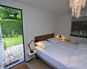 Slaapkamer met directe toegang tot de tuin in Vakantiehuis 't Hoogelandt 202 - Aan Zee, Texel, ideaal voor ontspanning.