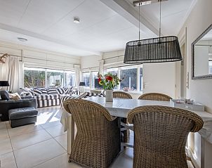 Eetgedeelte in Bungalowpark 't Hoogelandt, De Dennen, Texel, met rieten stoelen en bloemen op tafel.