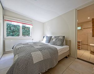 Slaapkamer met tweepersoonsbed in Bungalowpark 't Hoogelandt, De Dennen, Texel, naast badkamer.