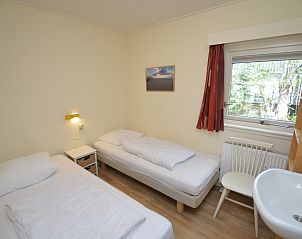 Tweede slaapkamer in Vakantiehuis De Nagtegaal 19, De Dennen Texel met eenpersoonsbedden en raam.