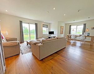 Open woonkamer en eetruimte in Appartement Bos en Duin 40, De Dennen, Texel met uitzicht op het groene landschap.