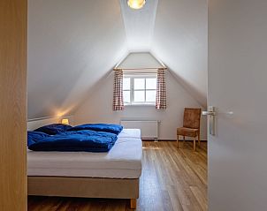 Lichte slaapkamer in 't Mienthuis - De Prins, vakantiehuis in De Dennen, Texel met houten vloeren en groot raam.