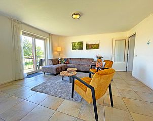 Stijlvolle zithoek in Appartement Bos en Duin 43, De Dennen, Texel met toegang tot het balkon en uitzicht op het groen.