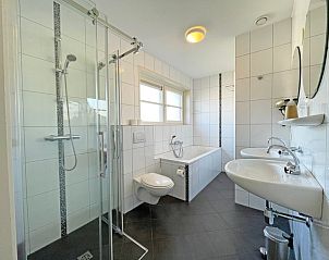 Moderne badkamer van Appartement Bos en Duin 43, De Dennen, Texel met douche, bad en dubbele wastafel.