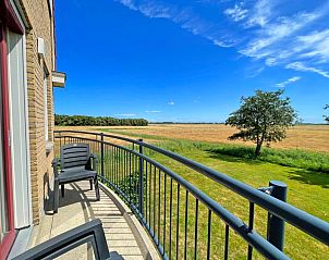 Balkon van Appartement Bos en Duin 43, De Dennen, Texel met prachtig uitzicht op de groene omgeving en blauwe lucht.
