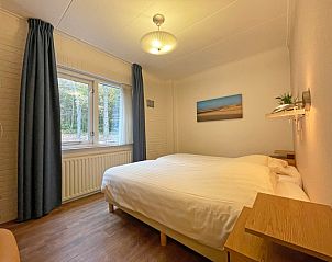 Comfortabele slaapkamer met tweepersoonsbed in Appartement Bos en Duin 15, De Dennen, Texel met uitzicht op de bosrijke omgeving.