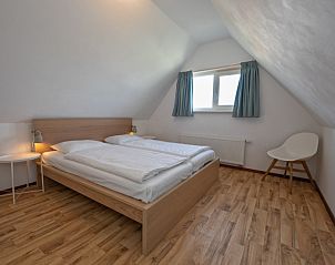 Slaapkamer op zolder in Huisje 6, Texel. Knusse sfeer met houten vloer en dakraam.