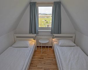 Tweede slaapkamer in Huisje 6, De Dennen, Texel met twee eenpersoonsbedden en uitzicht op het landschap.