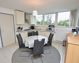 Eetkamer met ronde tafel in Vakantiehuis de Parel 194, De Dennen, Texel met uitzicht op de tuin.