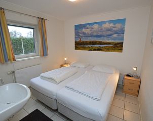 Sfeervolle slaapkamer in Vakantiehuis de Parel 194, De Dennen, Texel met tweepersoonsbed en kunstwerk.