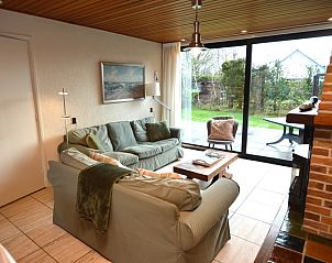 Gemtliches Wohnzimmer im Holiday home de Parel 258, De Dennen, Texel, mit bequemen Sofas und Blick auf den Garten.