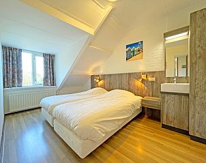 Schlafzimmer mit zwei Betten im Appartement Bos en Duin 36, De Dennen, Texel mit stimmungsvoller Beleuchtung.