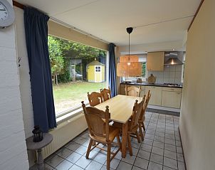 Eethoek in Bungalow Verste Coogh 56, De Dennen, Texel, met uitzicht op de tuin, ideaal voor gezellige maaltijden.