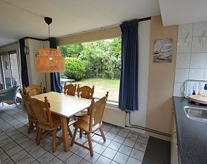 Eetkamer in Bungalow Verste Coogh 56, De Dennen, Texel, met grote ramen en zicht op de groene tuin.