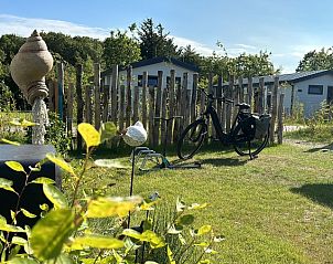 Grner Garten mit Fahrrad im Chalet Wulk auf Vakantiepark de Bremakker, umgeben von Natur in De Dennen, Texel.