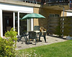 Terrasse im Ferienhaus Carnation in De Dennen, Texel mit Gartenmbeln und Sonnenschirm.