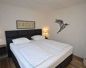 Slaapkamer in Vakantiehuis de Parel 244, De Dennen, Texel met comfortabel bed en sfeervolle verlichting.