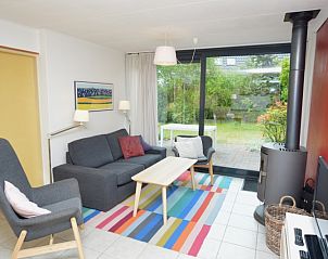 Gemtliches Wohnzimmer des Ferienhauses de Parel 286 in De Dennen, Texel, mit farbenfroher Einrichtung und Gartenblick.