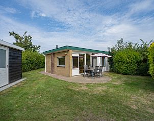 Bungalow Uterste Coogh 98 in De Dennen, Texel biedt een gezellig terras met tuinmeubilair omringd door groene natuur.