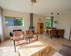 Ruime woonkamer in Bungalow Uterste Coogh 98, De Dennen, Texel met eetkamer en uitzicht op de groene omgeving.