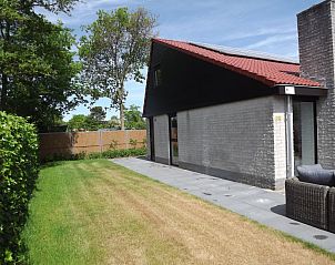 Seitenansicht des Ferienhauses Gortersmient 322 in De Dennen, Texel, umgeben von einem grnen Garten.