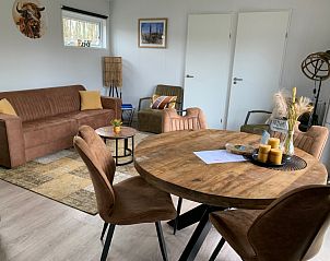 Gezellige woonkamer van Vakantiepark De Bremakker - Chalet 1140 in De Dennen, Texel met comfortabele zitruimte en houten eettafel.