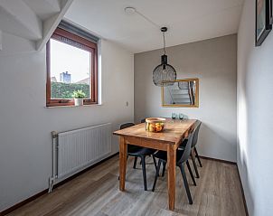 Eetkamer in Vakantiehuis Gortersmient 228 De Dennen Texel met houten tafel en raam.