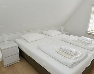 Sfeervolle slaapkamer in 't Wambas vakantiehuis, De Dennen, Texel met comfortabele bedden en serene uitstraling.
