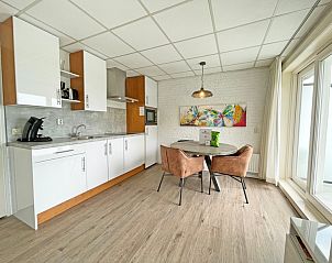 Compacte keuken in Appartement Bos en Duin 19, De Dennen, Texel met eethoek en kleurrijk schilderij.
