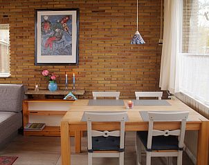 Gemtliches Esszimmer im Bungalowpark Uterste Coogh - Bungalow 84, De Dennen, Texel, mit stimmungsvollem Mobiliar und Kunst an der Wand.