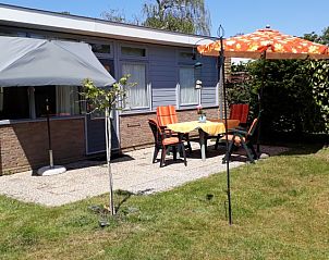 Sonnige Terrasse im Bungalowpark Uterste Coogh - Bungalow 84, De Dennen, Texel, mit bunten Sthlen und Sonnenschirm zum Entspannen.