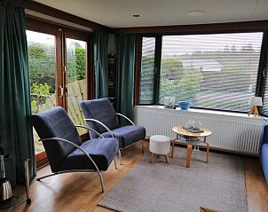 Lichte woonkamer in Vakantiepark De Koorn-aar - Chalet 102 type C, De Dennen, Texel met ruime zitplaatsen en uitzicht op de tuin.