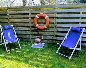 Zonnige tuin met ligstoelen in Vakantiepark De Koorn-aar - Chalet 102 type C, De Dennen, Texel, perfect voor relaxen.