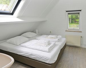 Ruime slaapkamer in vakantiehuis Turel, De Dennen, Texel met uitzicht op bos.
