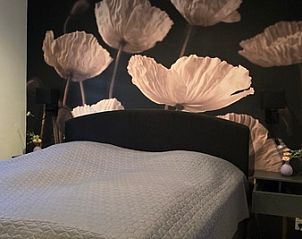 Slaapkamer in Helianthus vakantiehuis De Dennen Texel met sfeervolle wanddecoratie en luxe bed.