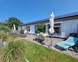 Sonnige Terrasse am Ferienhaus Boszicht in De Dennen Texel mit Liegesthlen und Sonnenschirm.