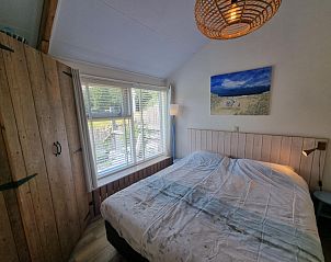 Schlafzimmer des Ferienhauses Boszicht in De Dennen Texel mit groem Fenster und stimmungsvoller Dekoration.