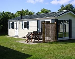 Auenansicht des Ferienparks De Koorn-aar Typ E in De Dennen, Texel mit sonniger Terrasse und grner Umgebung.