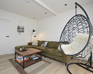 Stijlvolle woonkamer in Bungalowpark 't Luwe Land - Bungalow 13c, De Dennen, Texel, met hangstoel en comfortabele bank.